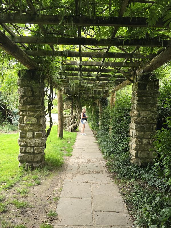 Shaz on a garden walk beneath a wisteria-covered pergola